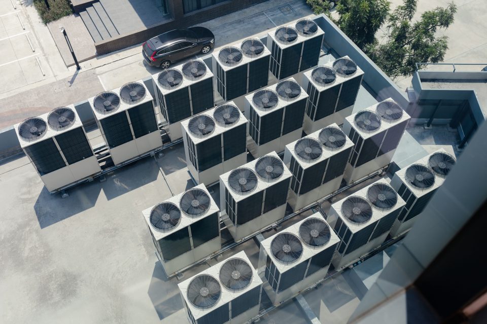 HVAC Regulations 2025-2026: Opportunities for OEMs – Part 1 2 Top view. Large row of buildings with rooftop fans used in air conditioning, refrigeration, heat pump systems, future green energy concept.